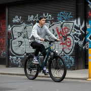 Person riding a bicycle in front of a graffiti-covered shutter.