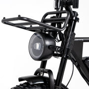 Close-up of a black electric bicycle frame with a front headlight, front cargo rack, fender, and knobby tire on a white background.