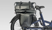 Black Enzug bicycle pannier bags mounted on the rear rack and seat tube of a blue bicycle, shown against a light gray studio background.