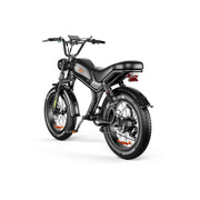 A black electric fat tire bike with a digital display, fenders, and knobby tires, photographed from a three-quarters rear angle on a solid white background.