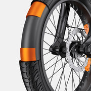 Close-up of a black bicycle tire with bright orange reflective bands, mounted on a black wheel with a visible disc brake and silver rim against a light gray background.