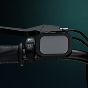 A black electronic handlebar mount holding a rectangular screen device, attached to a bicycle or e-bike handlebar with control buttons visible on the left, set against a dark teal gradient background.