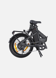A compact folding electric bicycle in matte black, shown from a side profile view against a solid light gray background. The bike features a black frame, black saddle, black tires, and a prominent orange accent ring on the wheel spokes.